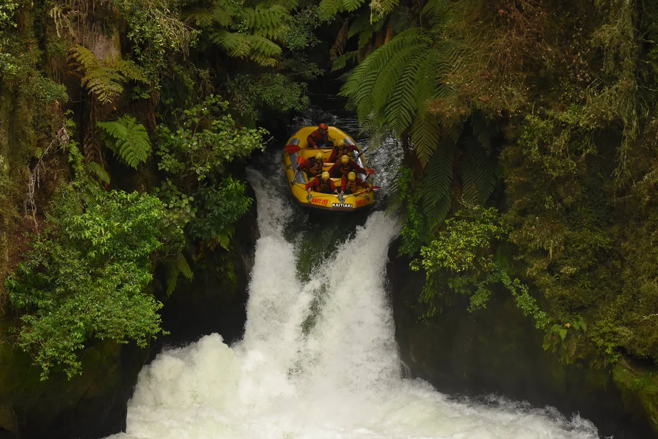 Kaitiaki Adventures Raft poised at the brink of Tutea Falls, the world's highest commercially rafted waterfall, ready for an exhilarating descent into the churning waters below.