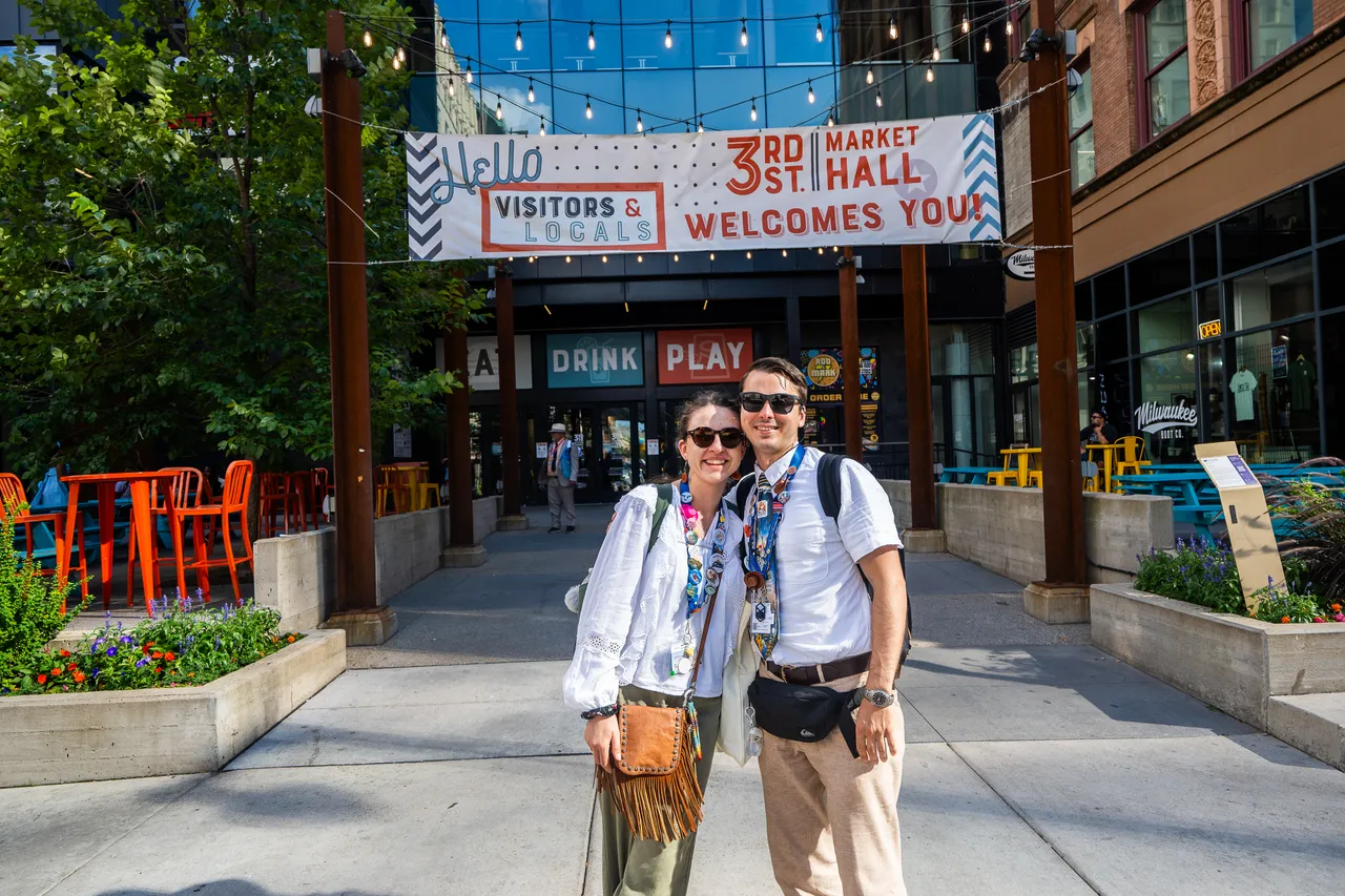 A smiling couple poses under the welcome banner outside 3rd Street Market Hall.