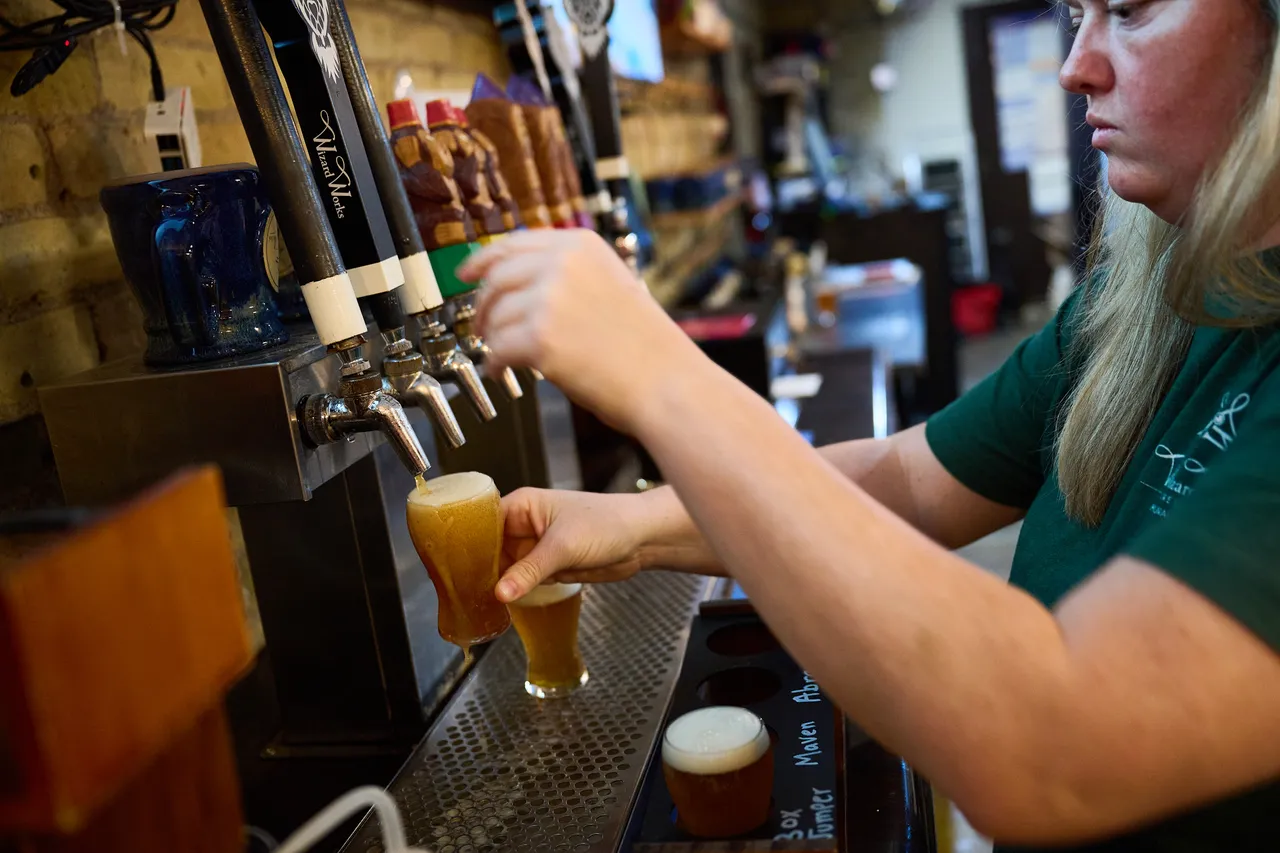 A bartender pours golden beer from a tap into a glass behind the bar.