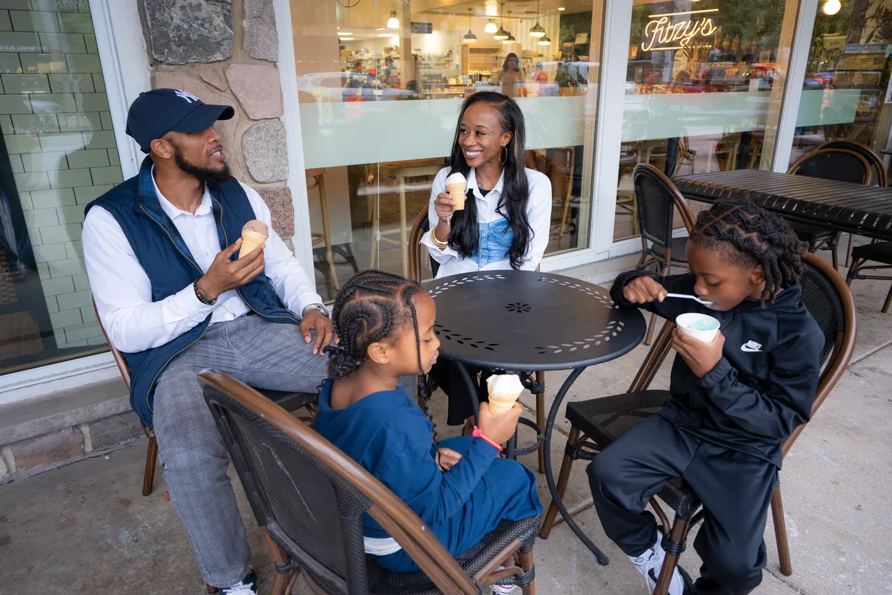 A family shares ice cream around a small table outside a café.