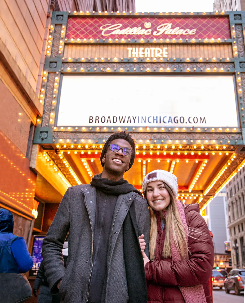 Couple standing outside of the Cadillac Palace Theatre marquee in Chicago in the winter
