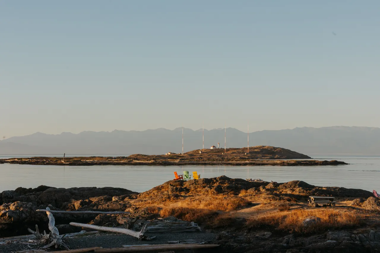 Evening calm by the water with mountains in background and chairs