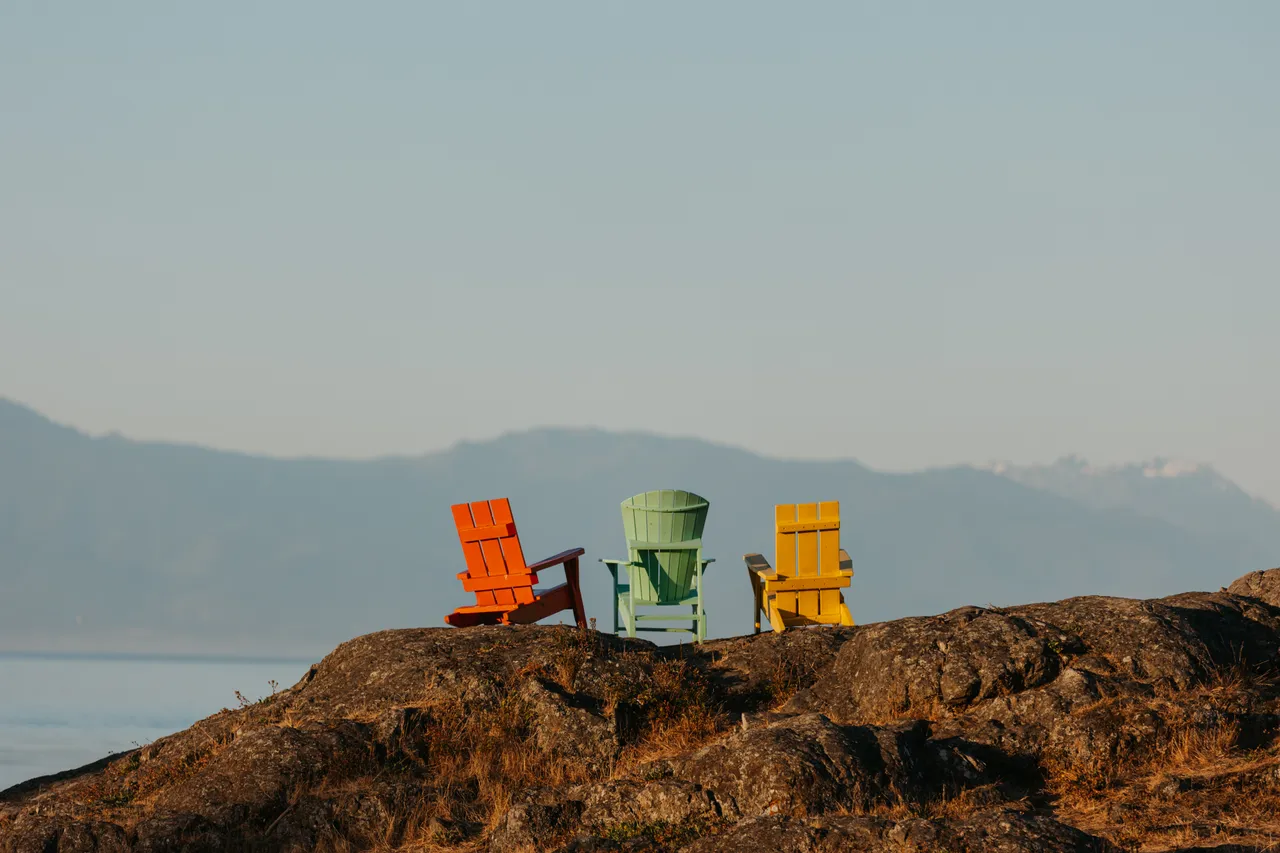 Colourful chairs overlooking calm ocean and distant mountains