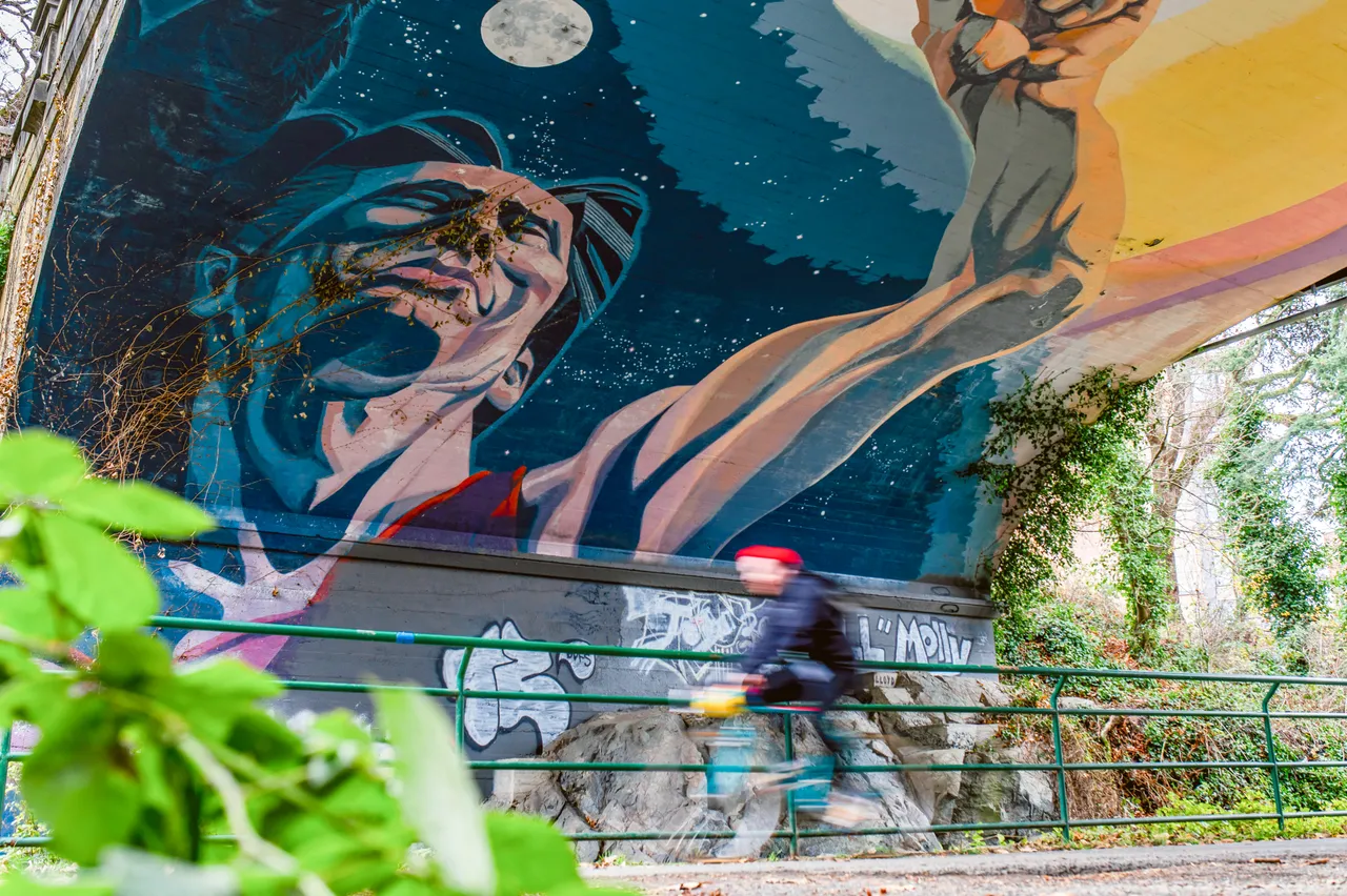 People cycling by street art - 2