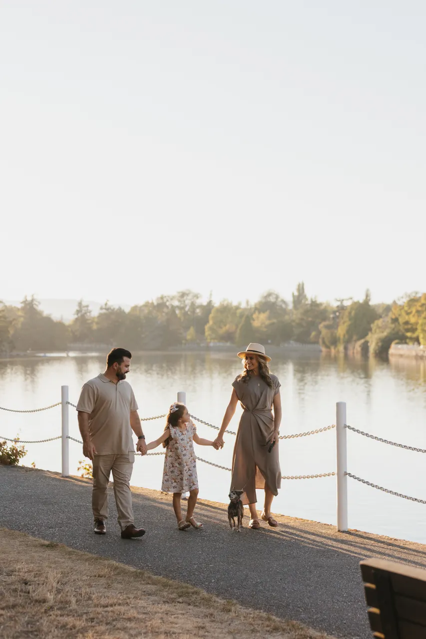 Family walking by a calm body of water on a sunny morning