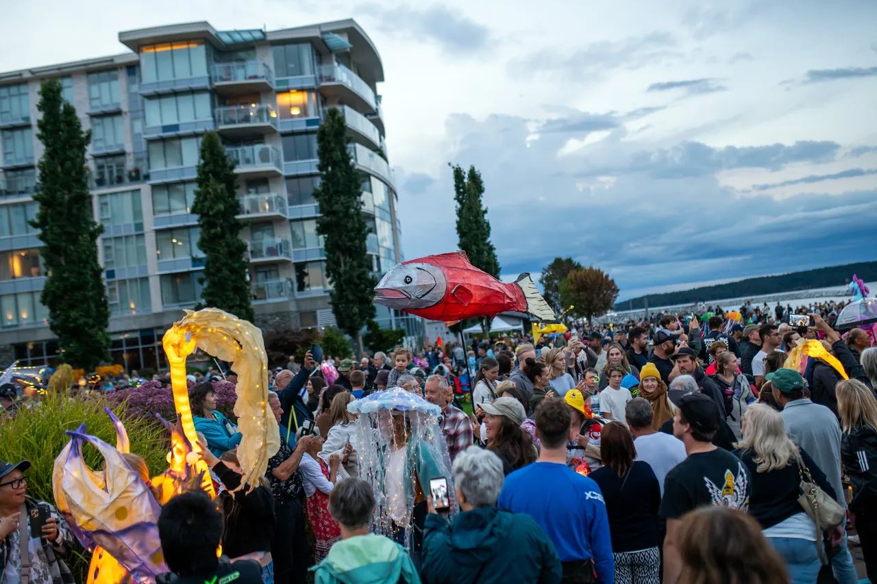 Illuminated Salmon Lantern Floating Above Crowd at Waterfront Festival