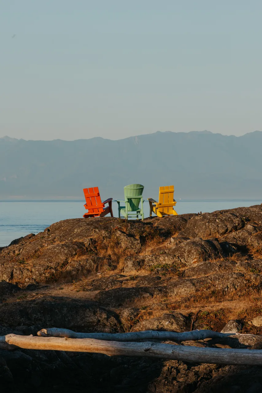 Colourful chairs overlook calm ocean and distant mountains