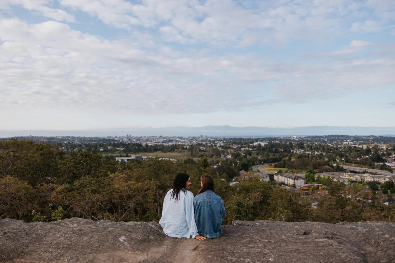Couple sitting on rocky hill overlooking distant city