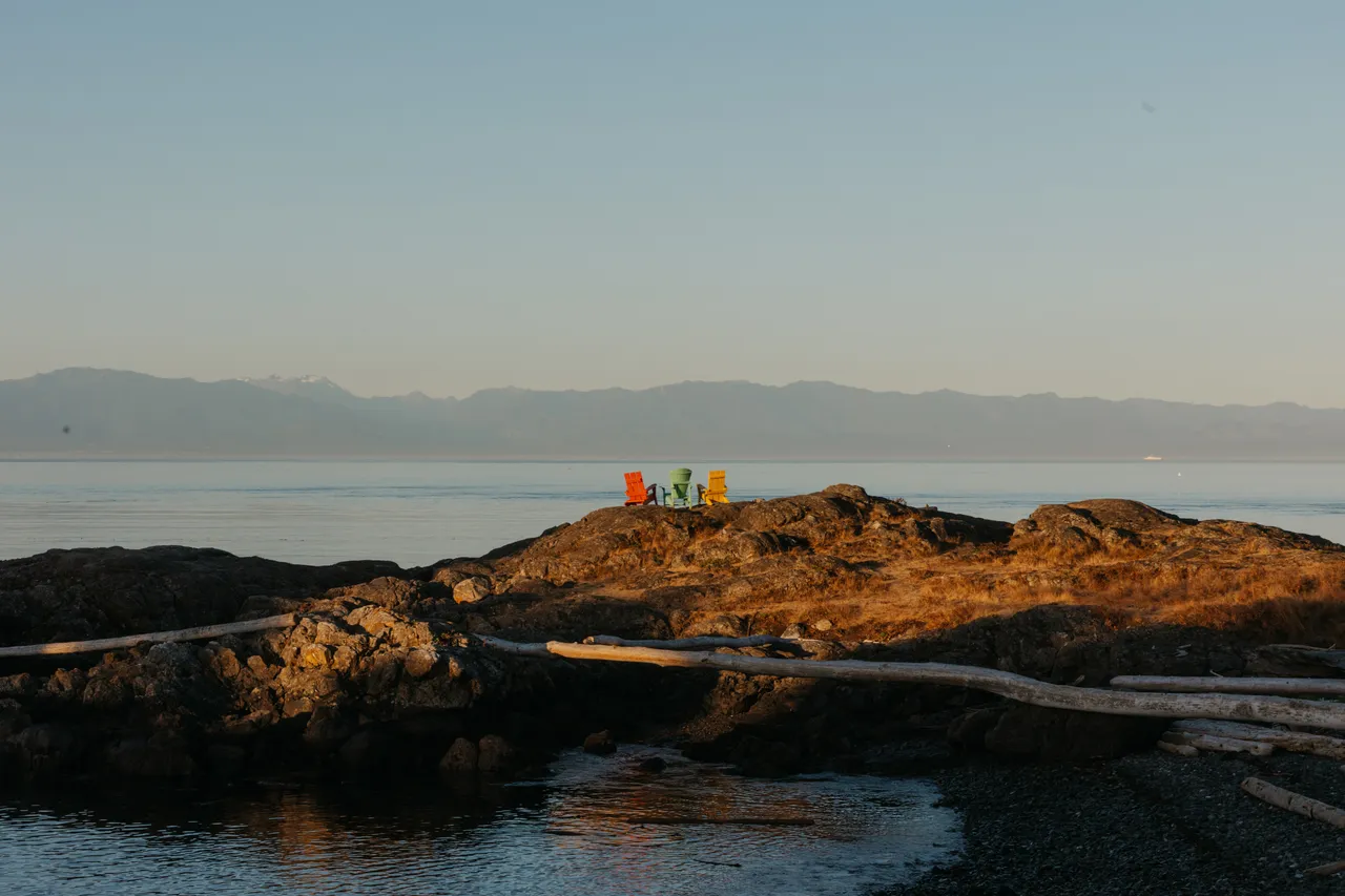 Quiet morning on a rocky island with chairs and mountains in background