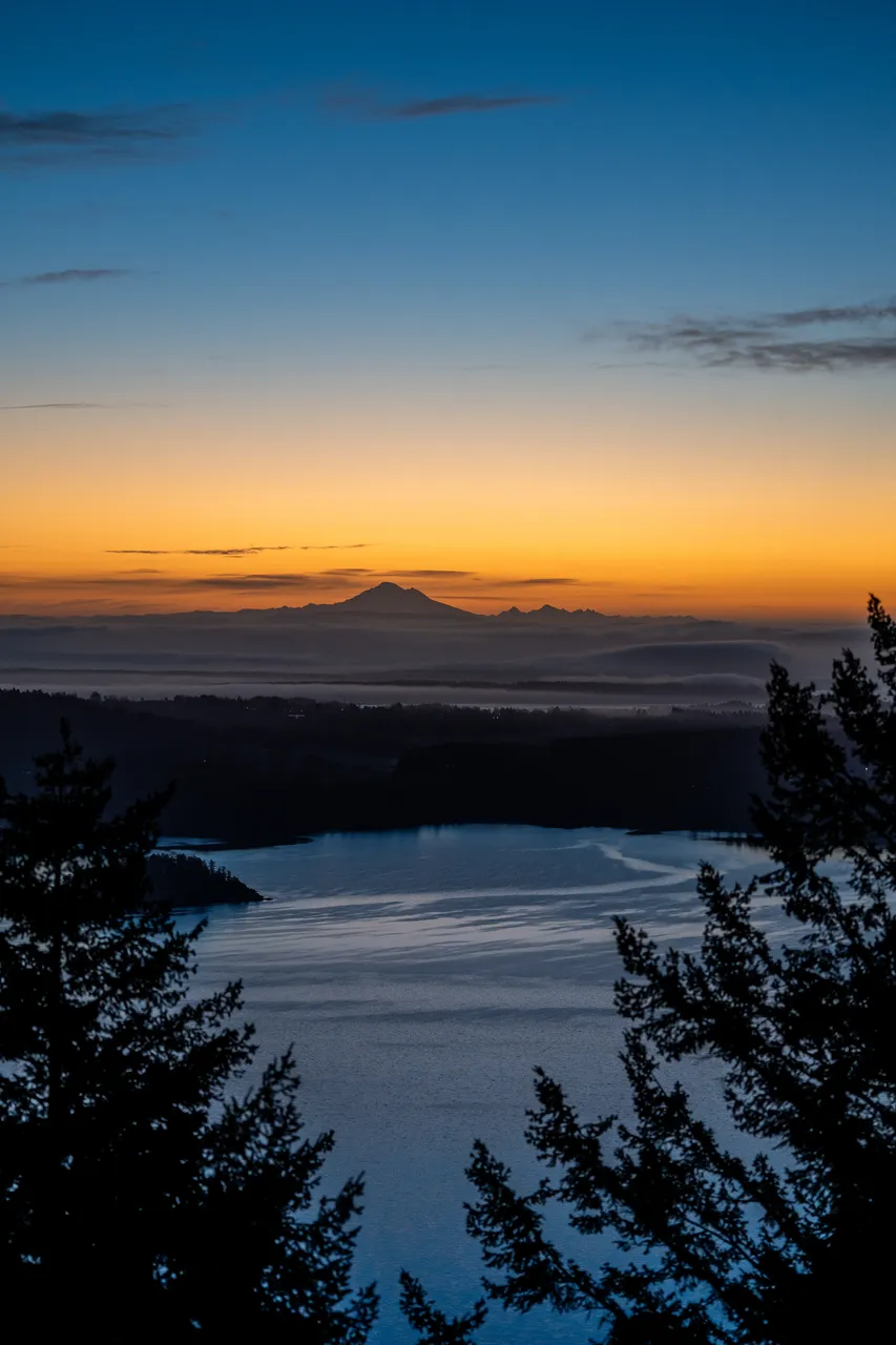 Aerial Photo of Greater Victoria Sunset with Trees in Foreground and Mountain Silhouette in Background