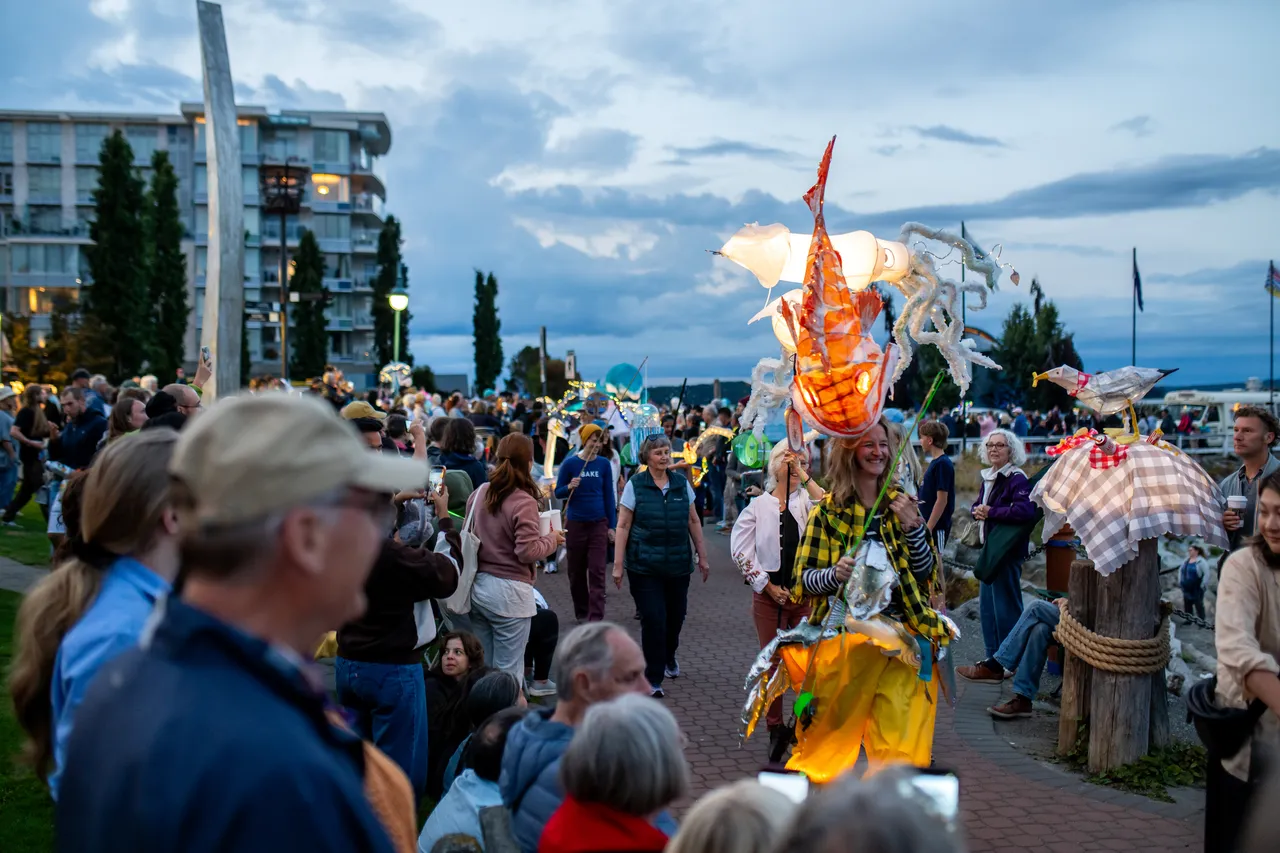 Performer Carries Illuminated Squid Lantern Through Waterfront Parade Crowd