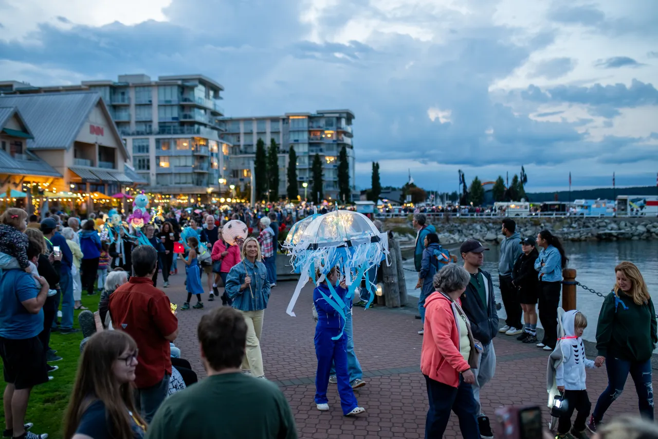 Performer in Jellyfish Costume Walks Waterfront Promenade During Lantern Parade