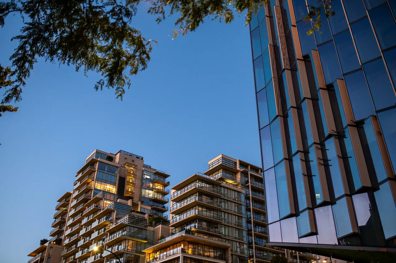 Terraced Condo Towers Beside a Faceted Glass Facade at Dusk