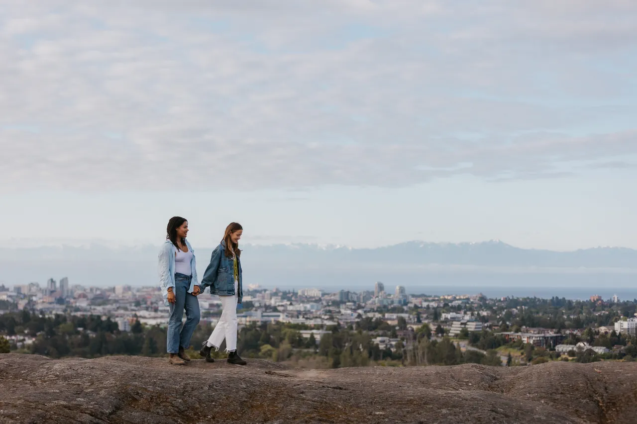 Couple walking above a scenic city view with clouds in background