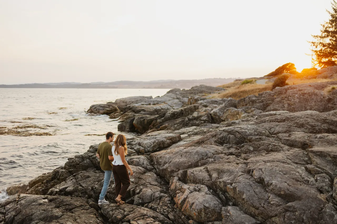 Couple strolling along rocky coastline at sunset
