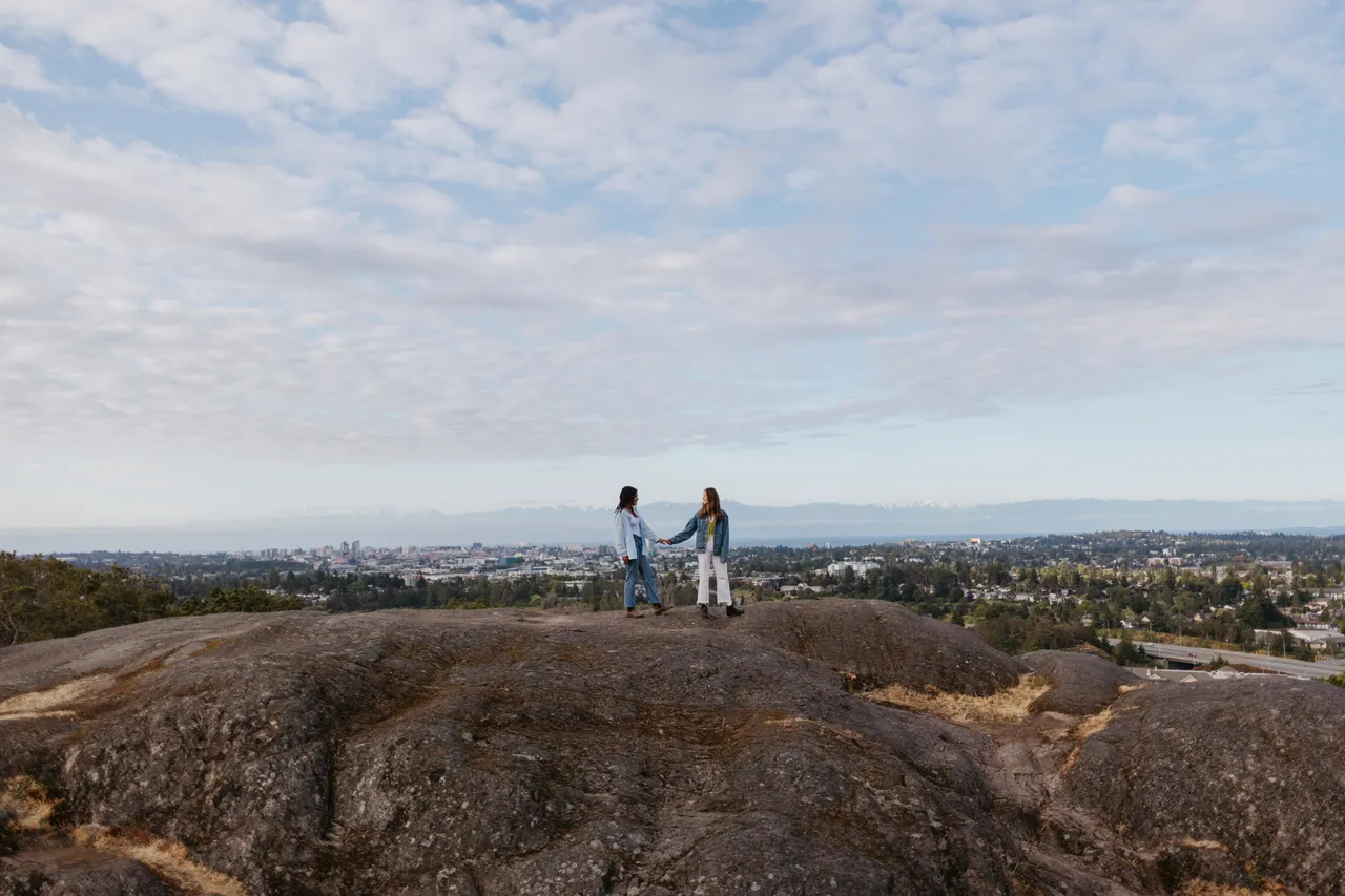 Couple standing on rocky hilltop overlooking city