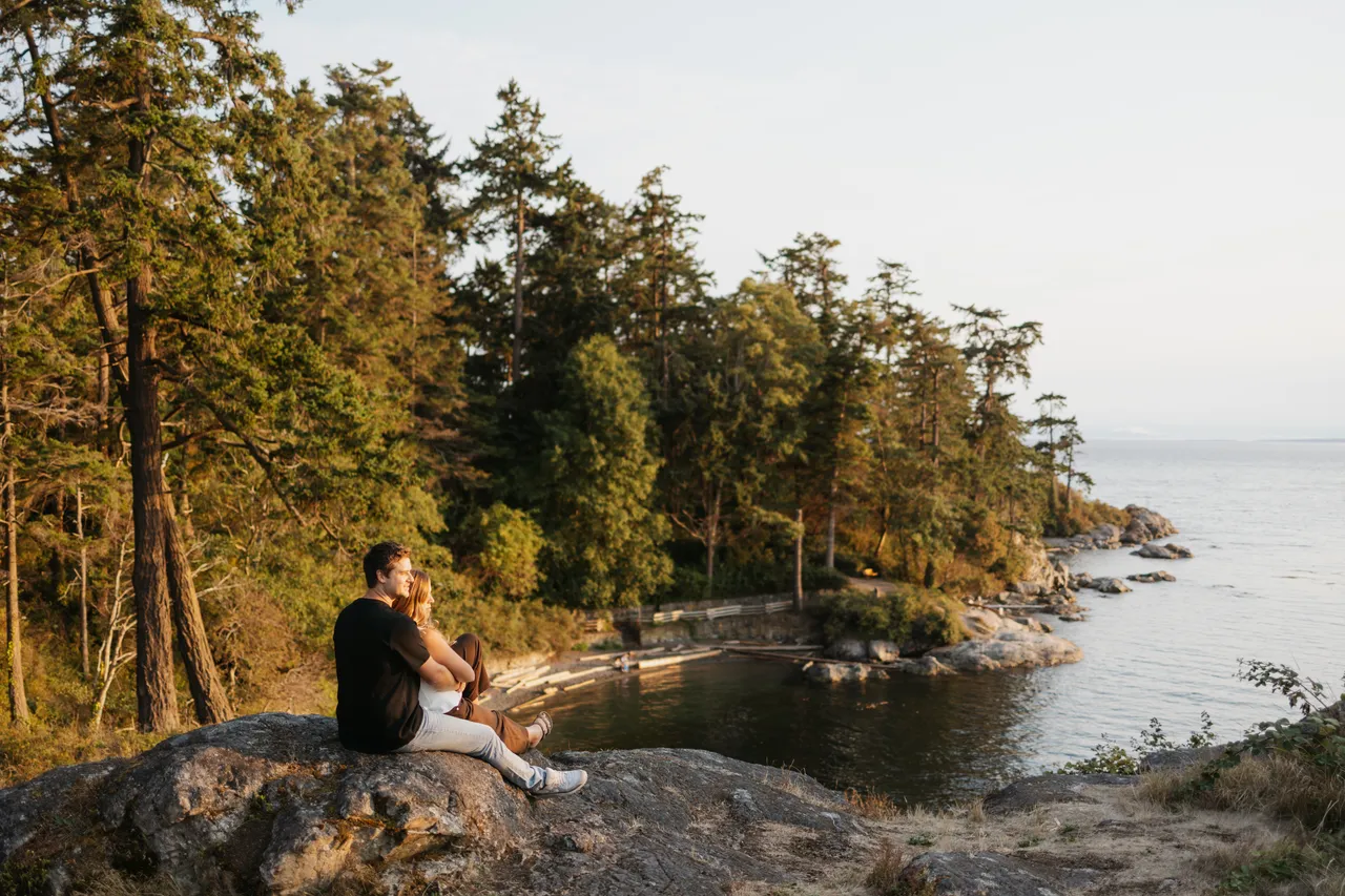 Couple overlooking a peaceful coastal inlet with trees in background