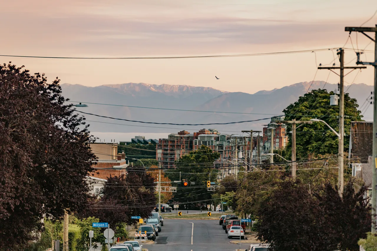 Quiet urban street leading towards mountains at dusk