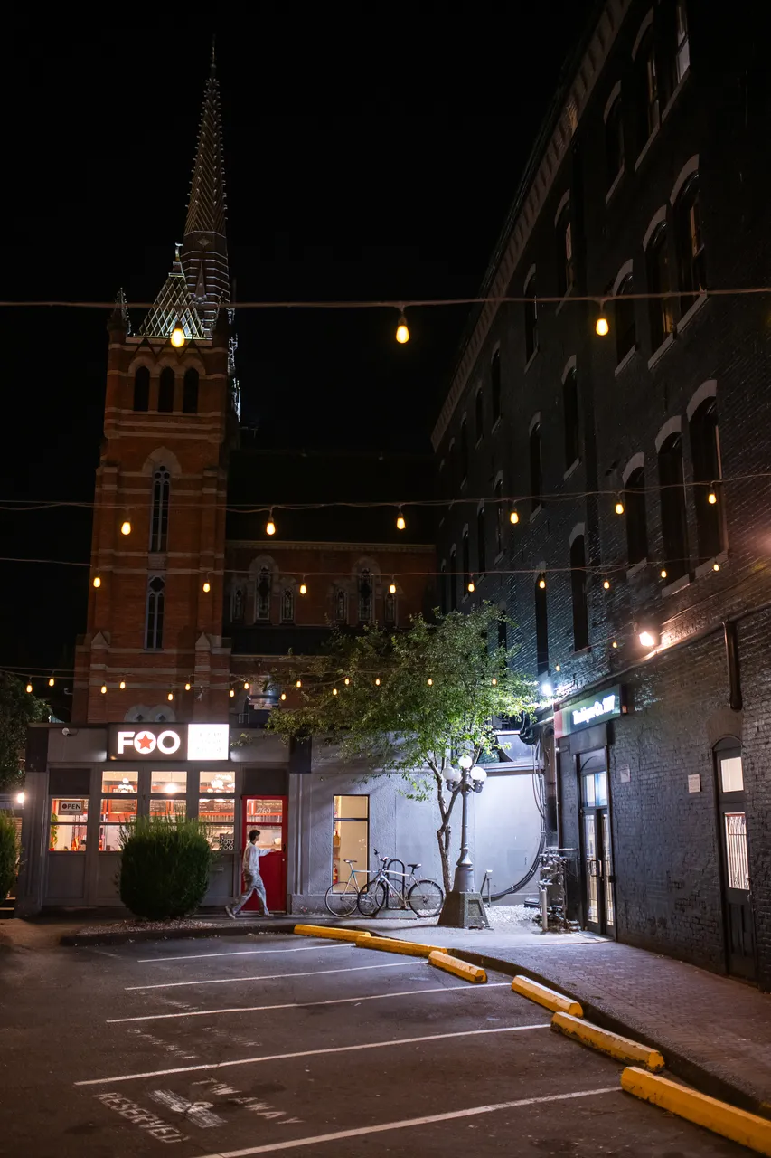 Quiet downtown street at night with a church spire rising behind the buildings