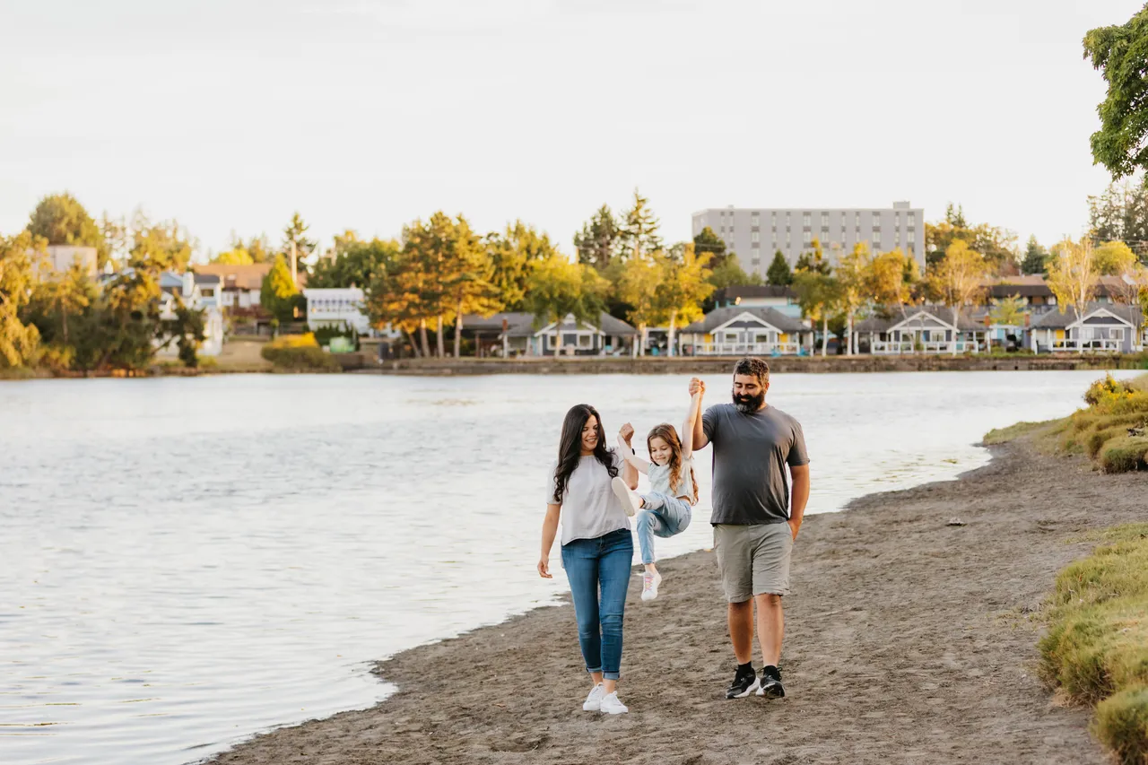 Family enjoying a sunny walk by the waterfront with housing in background