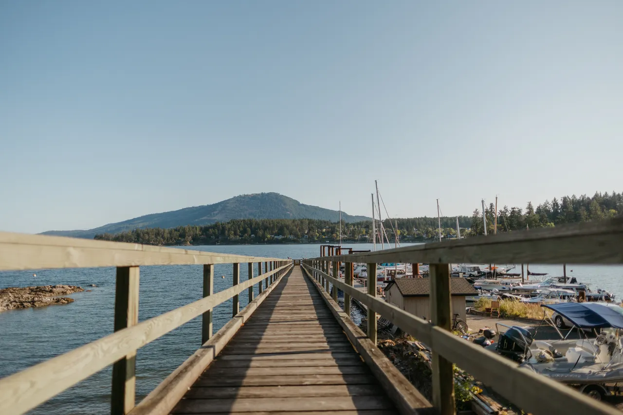 Wooden pier leading toward calm waters and distant hills