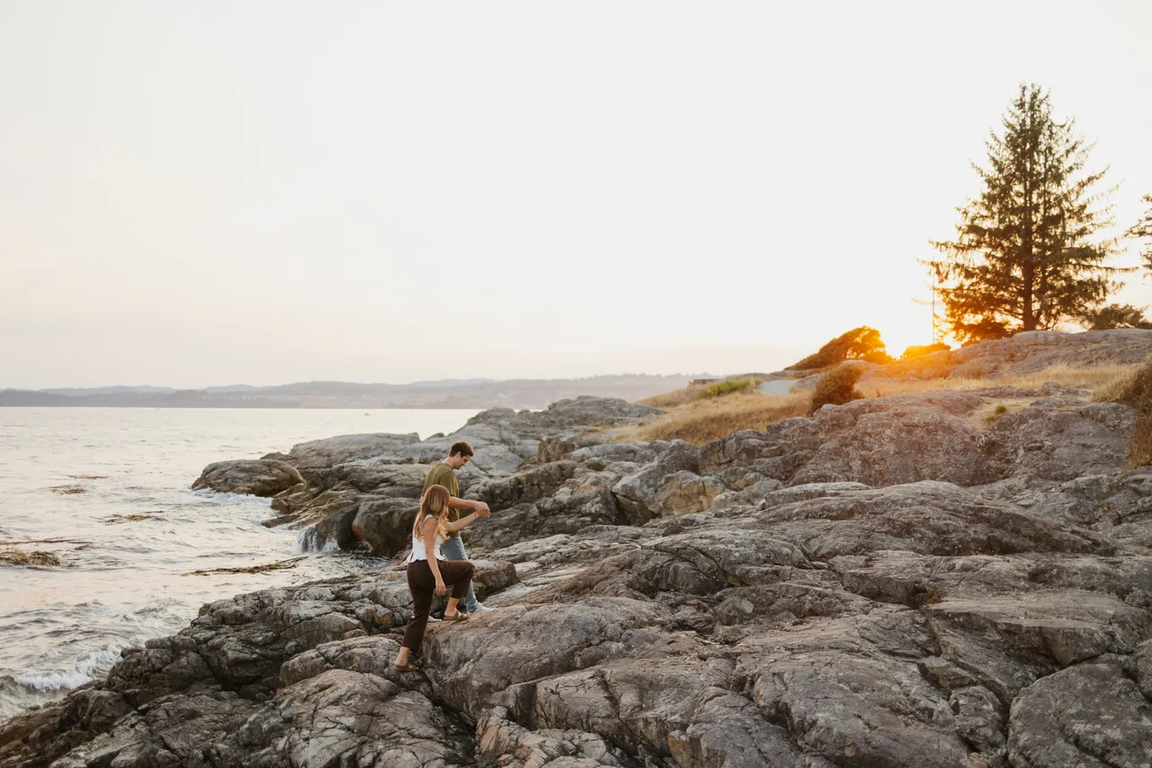 Couple enjoys sunset on rocky west coast shoreline