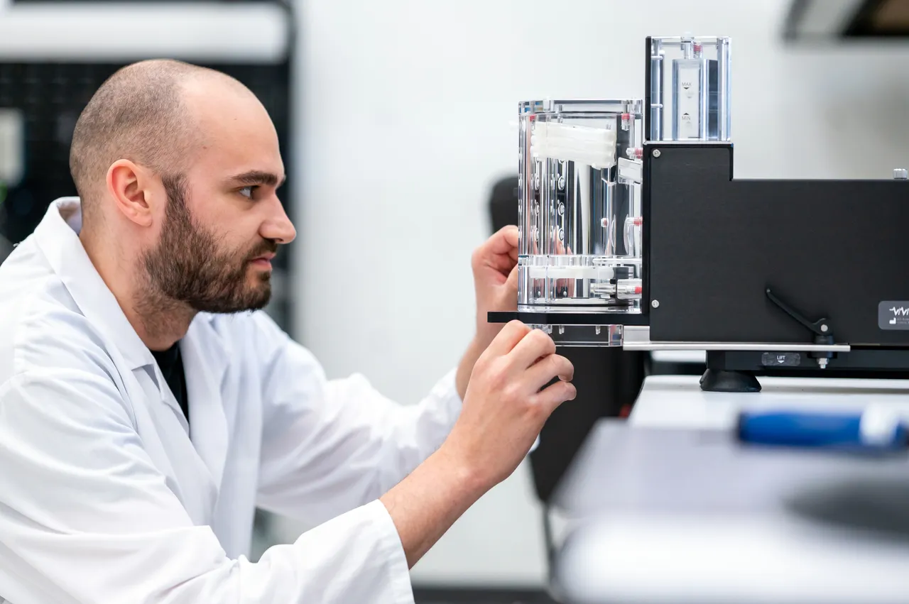 Employee in Lab Coat at Medical Company Looking at Glass