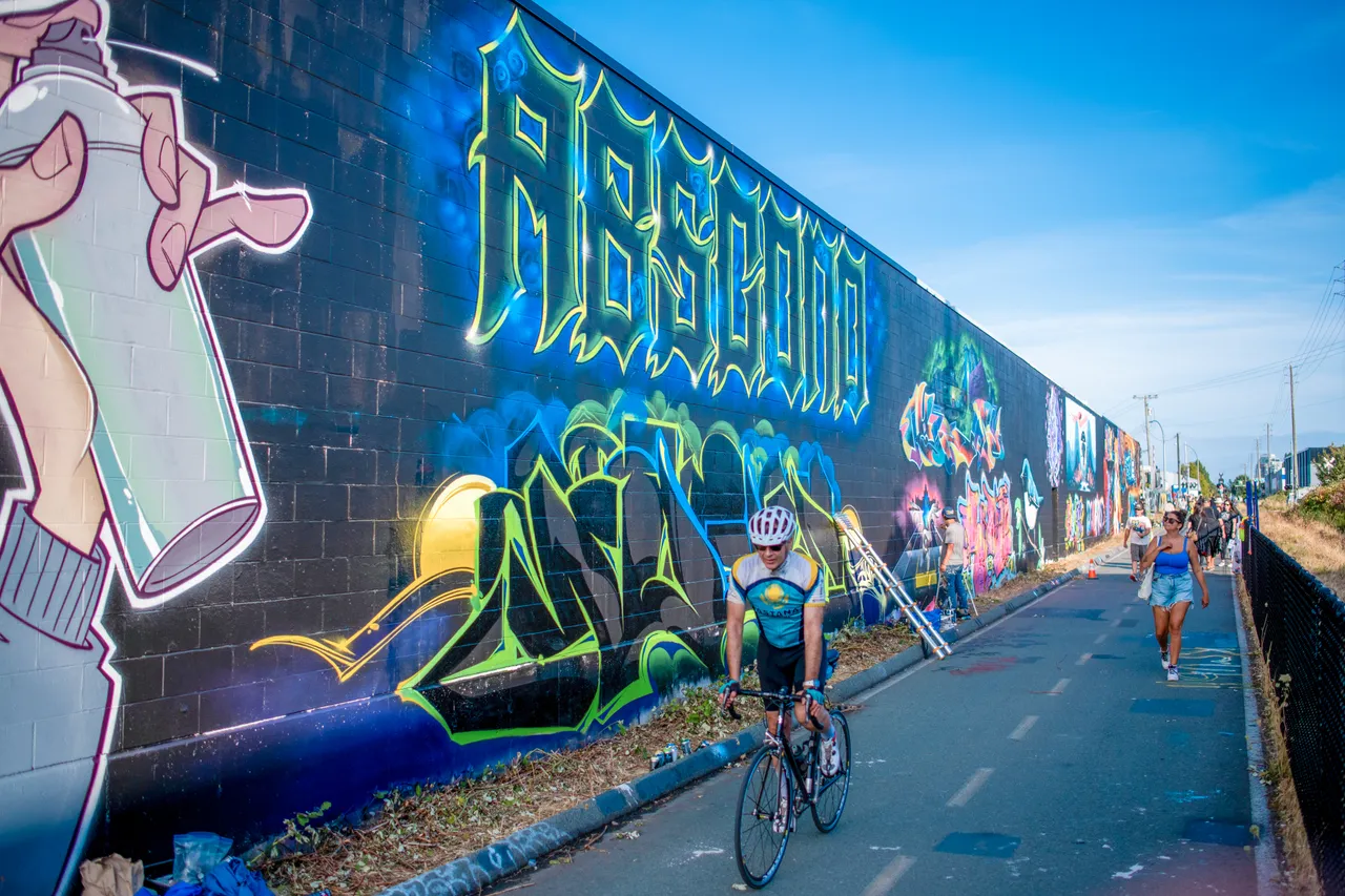 People cycling by street art - 3