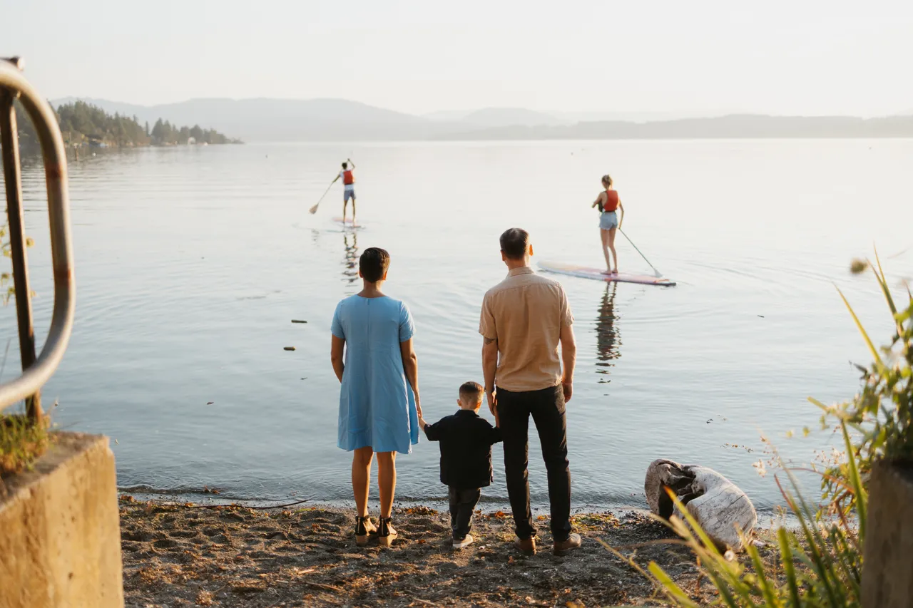 Peaceful paddleboarding on calm coastal waters at sunset with family looking onward