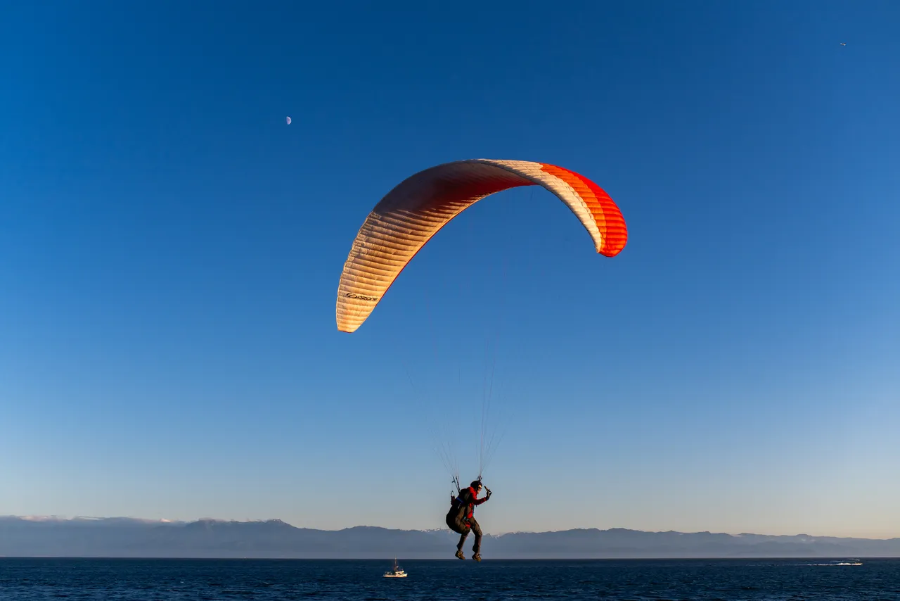 Person Paraglides with Mountains in Background