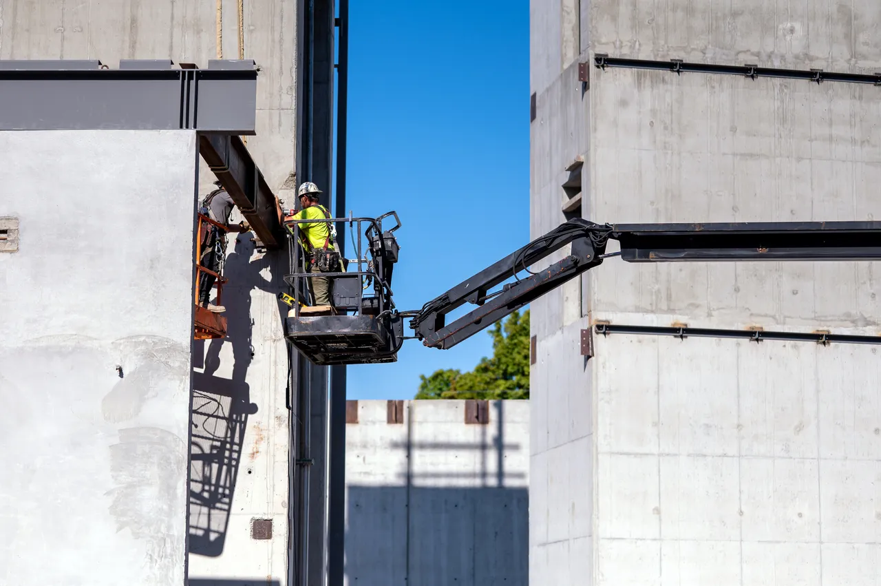 Construction Worker on Lift near Concrete Building