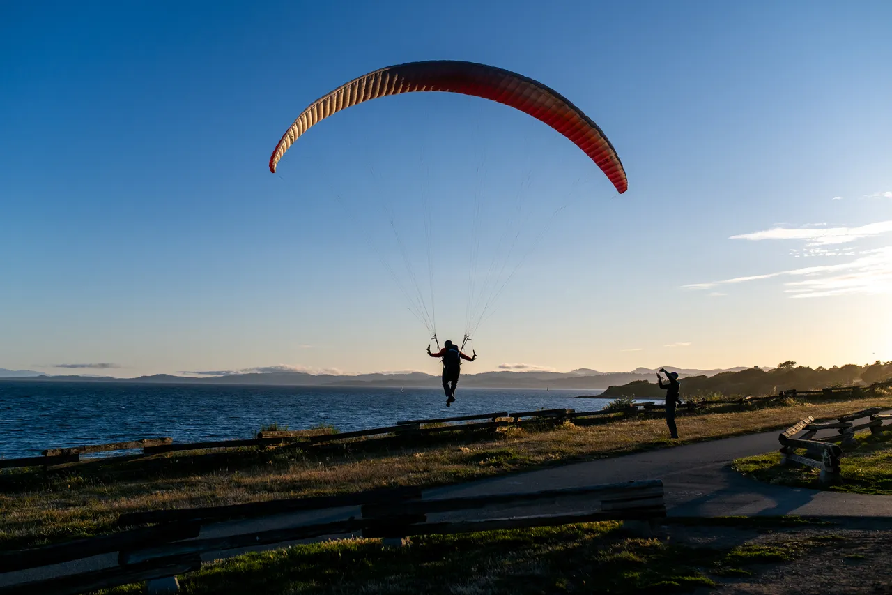Person Paraglides over Dallas Road at Dusk