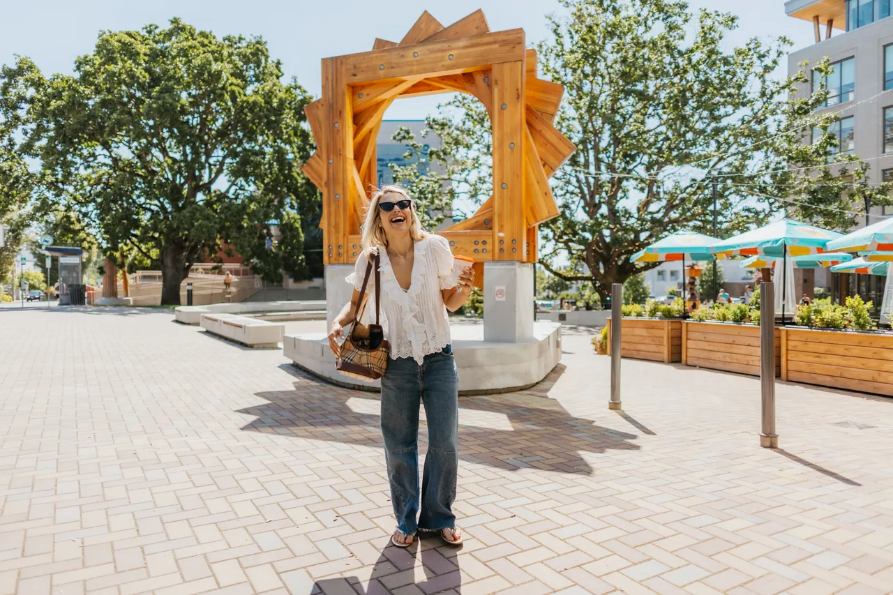 Person walking through urban plaza with sculptural arch