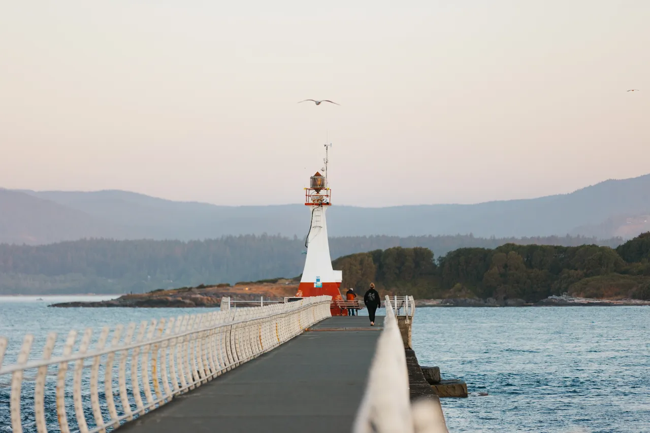 Lighthouse walkway stretching toward calm coastal horizon at dusk