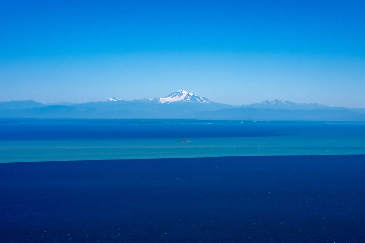 Blue Aerial Photo of Mountains and Sky with Single Boat