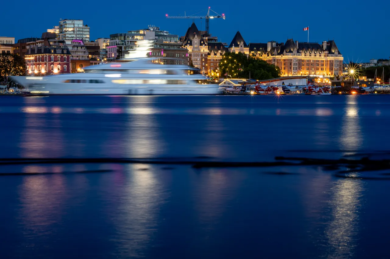 Yacht Moving Quickly Along Water with Hotel in Background 