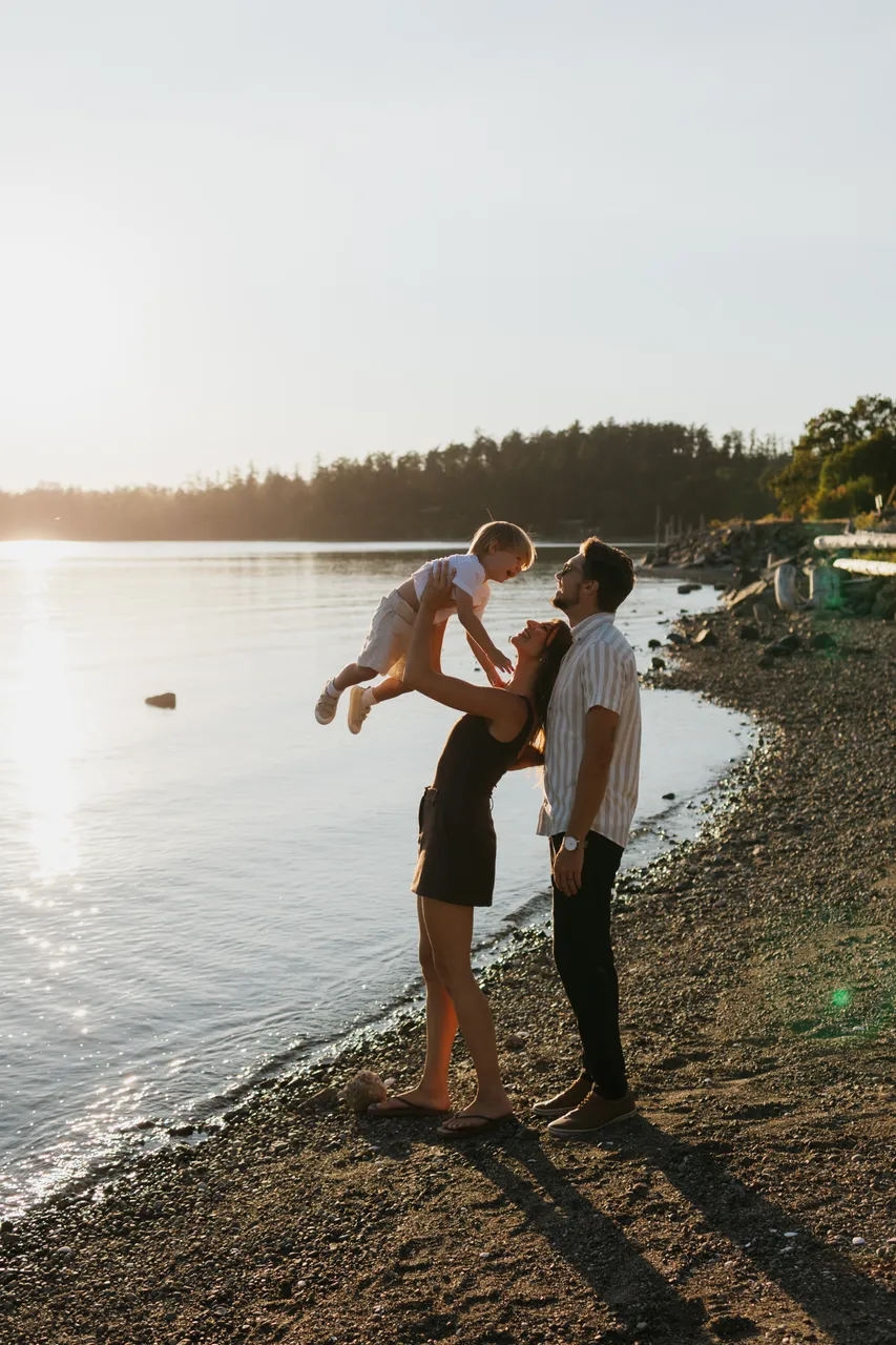 Family enjoying sunset by body of water with trees in background