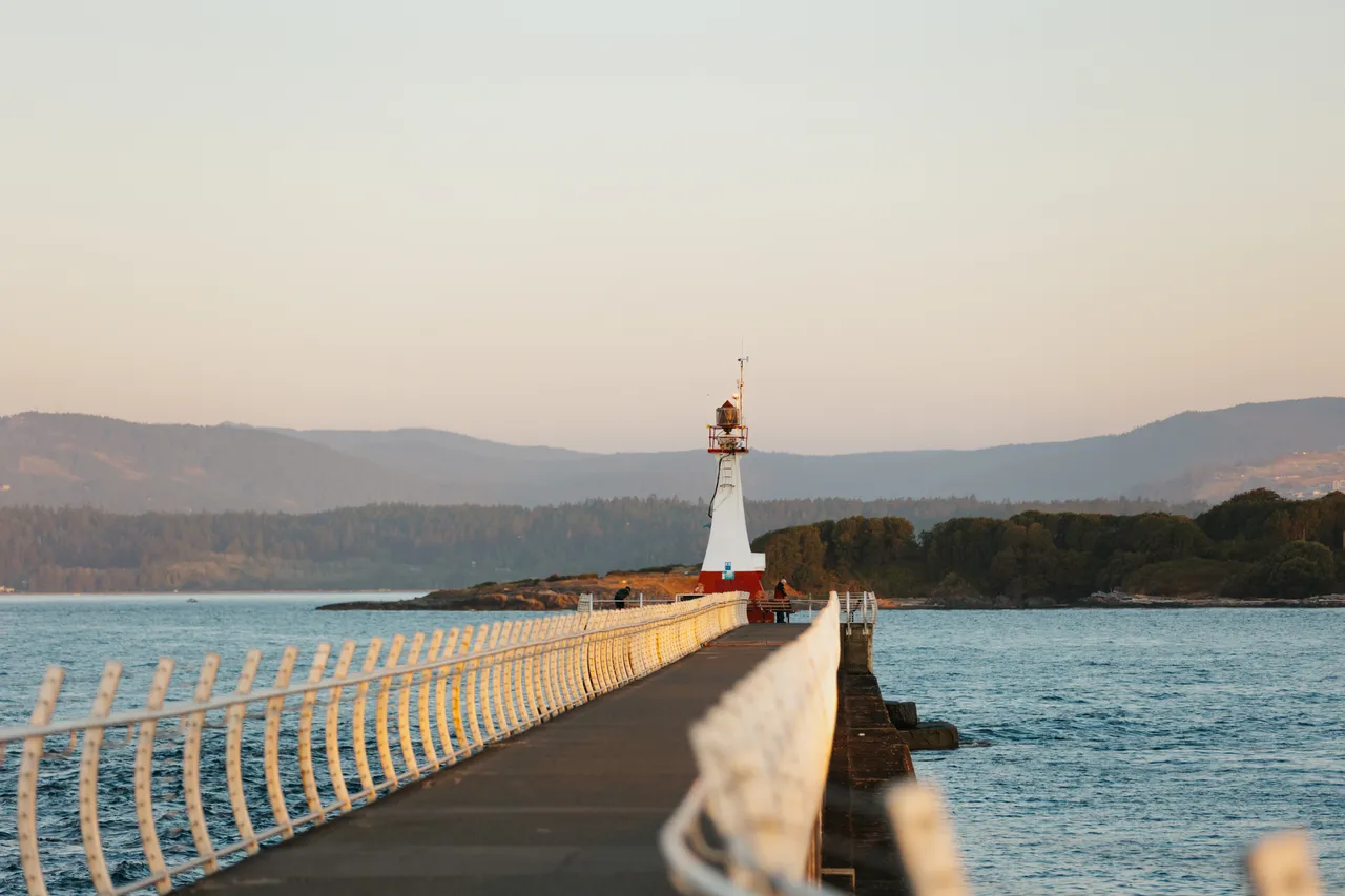 Peaceful evening view along a seaside walkway towards a lighthouse