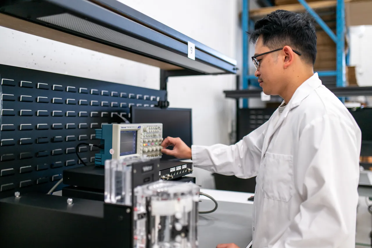 Person in Lab Coat at Facility Using Dials