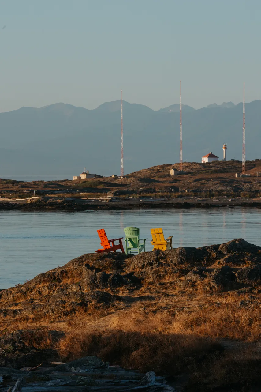 Colourful chairs overlooking calm coastal waters at sunset