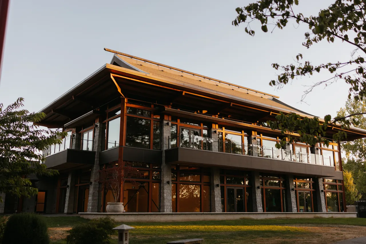 Modern timber pavilion surrounded by trees at sunset