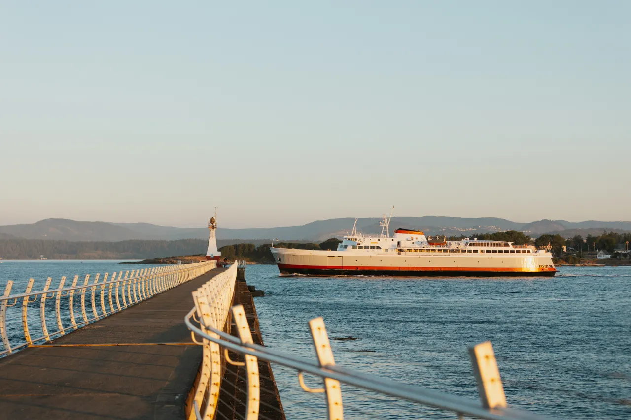 Ship passing lighthouse along peaceful coastal walkway