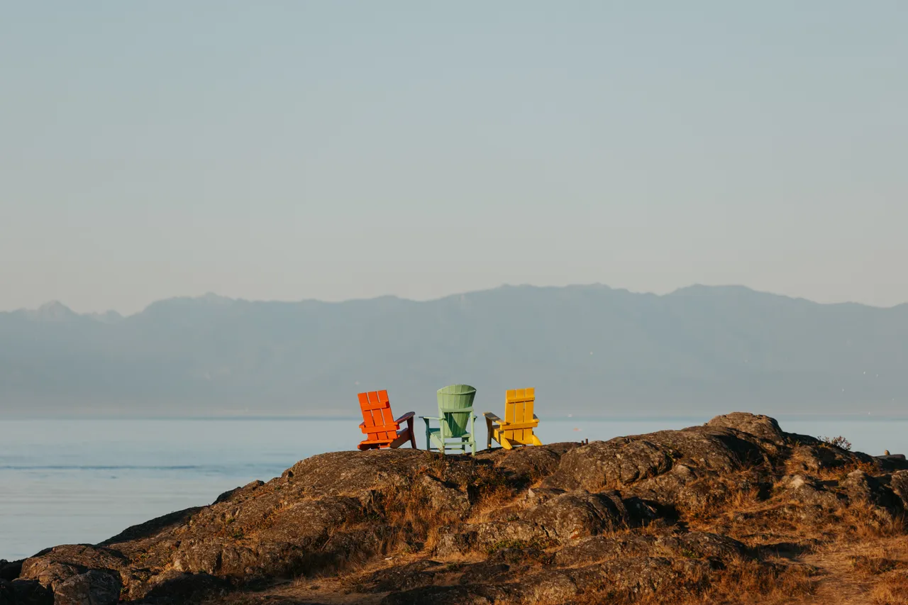 Calm ocean views near rocky coastal point with chairs