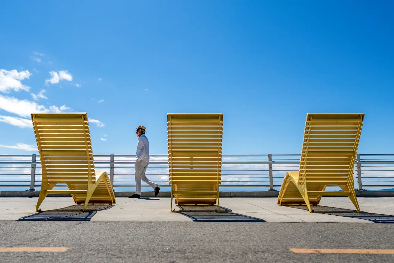 Man walking by lounge chairs - 1