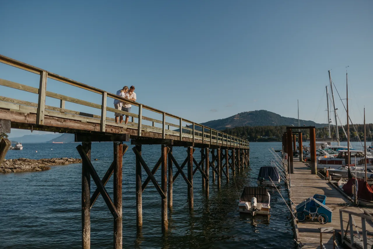 Wooden pier stretches over calm water beneath a clear sky near boats