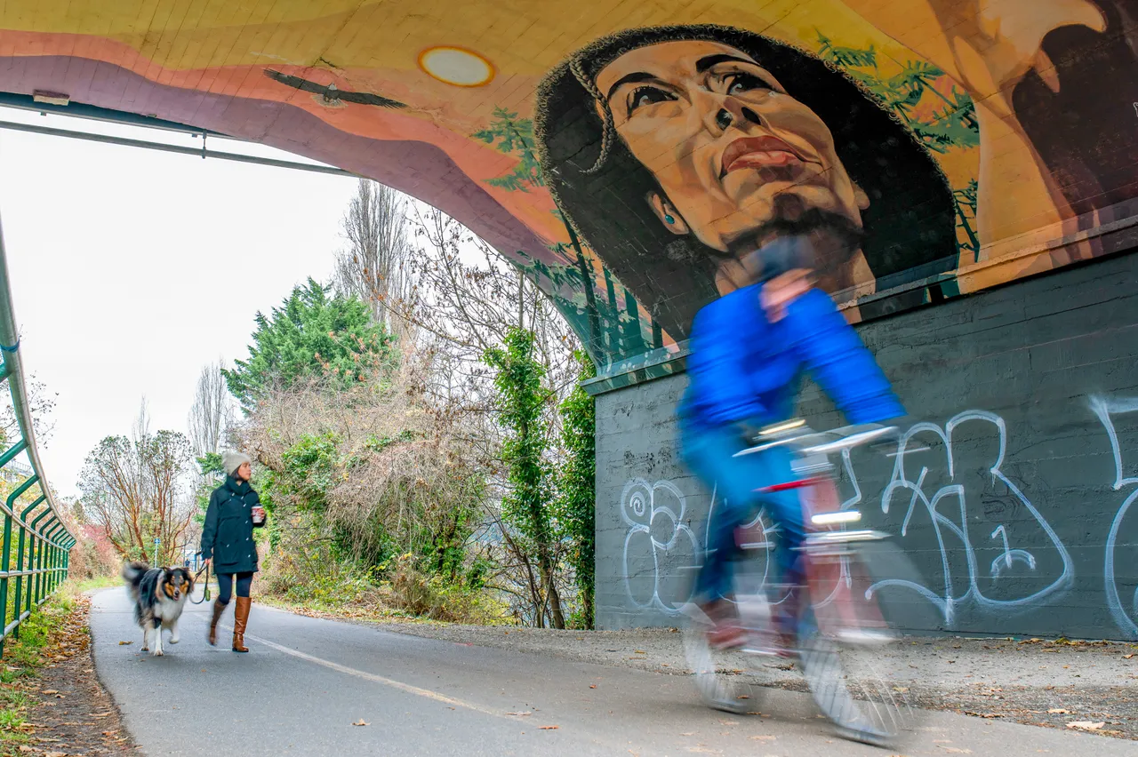 People cycling by street art - 1