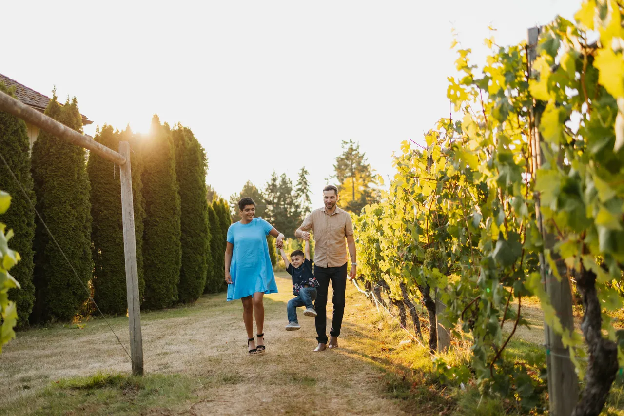 Family of three enjoying a sunny walk through vineyard rows