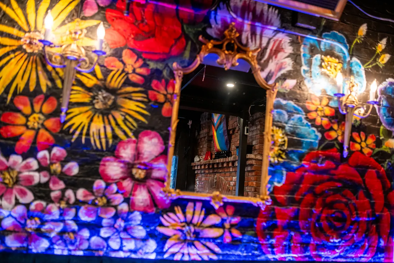Friends of Dorothy with Colourful Flower Mural and Mirror Showing Pride Flag