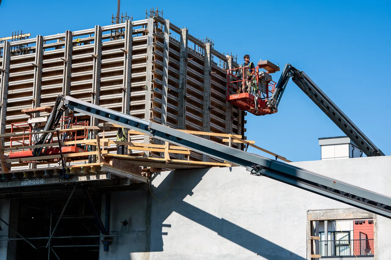 Construction Worker on Lift During Daytime Creating a Building
