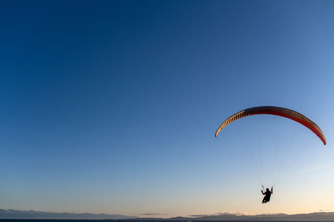 Person Paraglides with Large Sky in Background